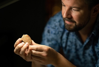 Dr Ben Shaw holding ancient pottery piece from Brooker Island, east of Papua New Guinea.
